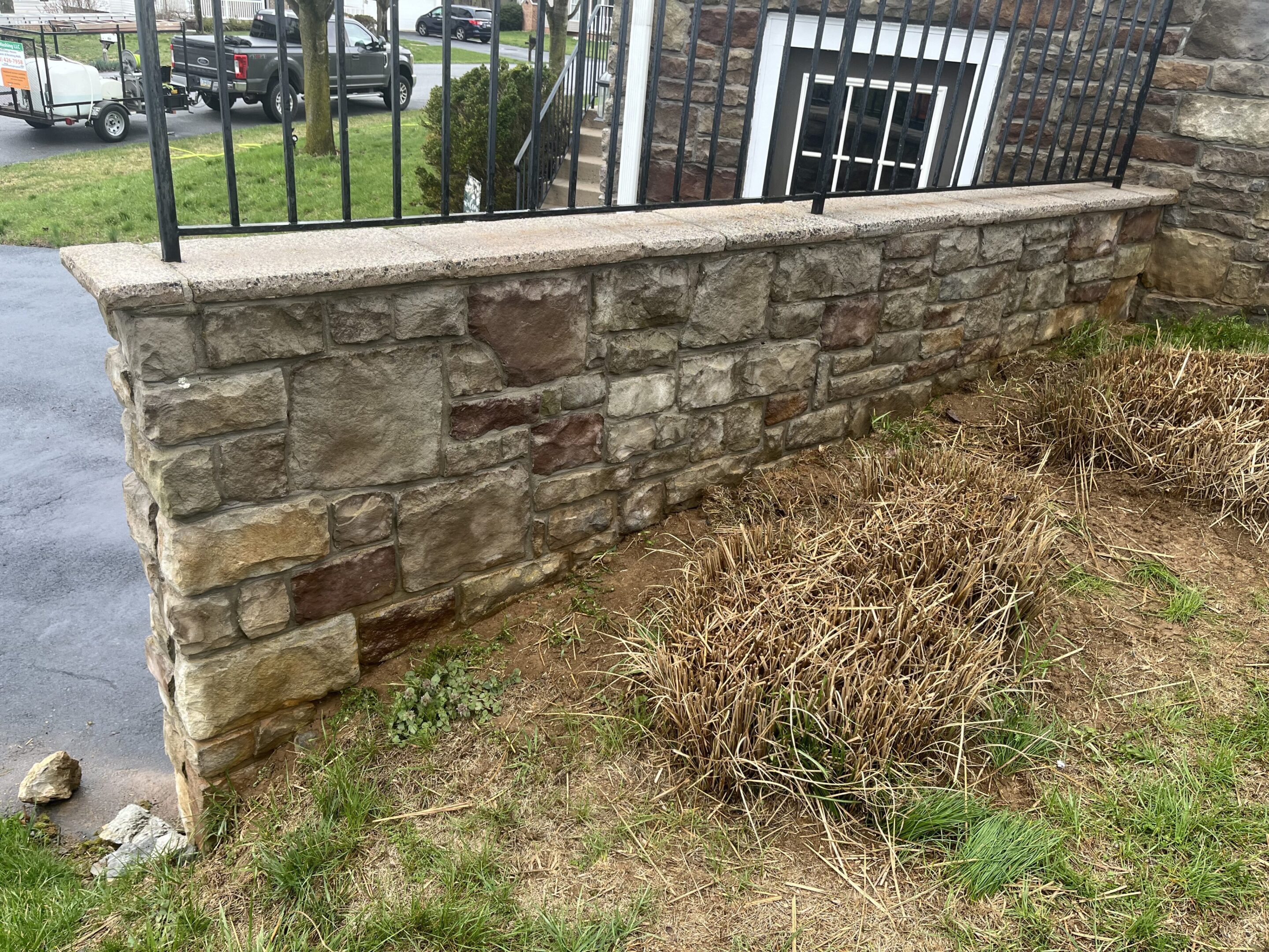 A stone retaining wall with a patch of dry grass beside it.