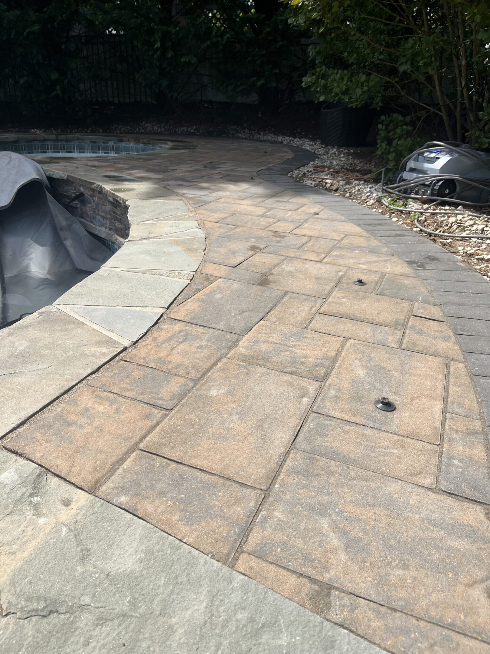 Newly installed stone patio with curved edge and natural tones.