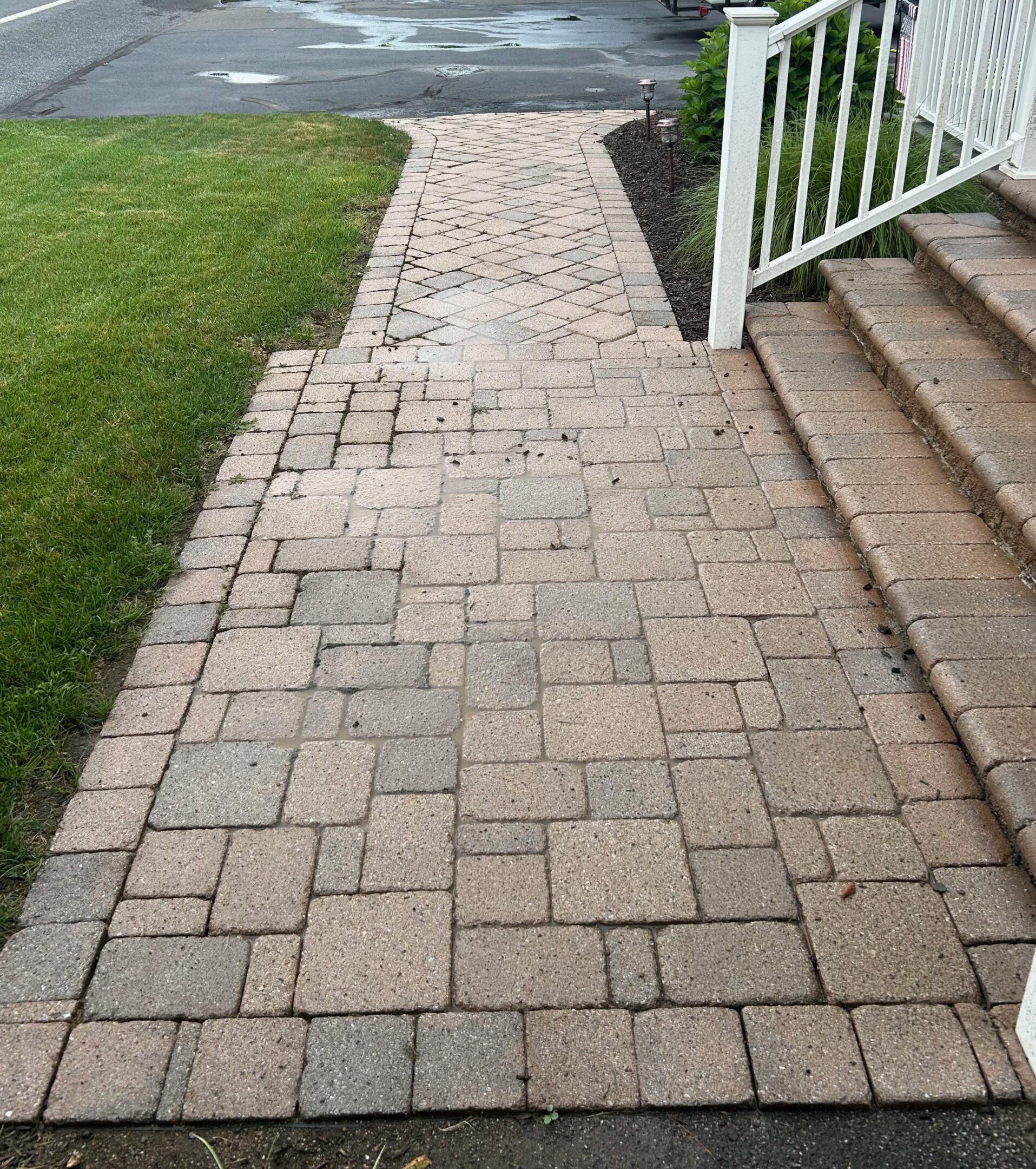 Stone pathway leading to stairs beside a green lawn.