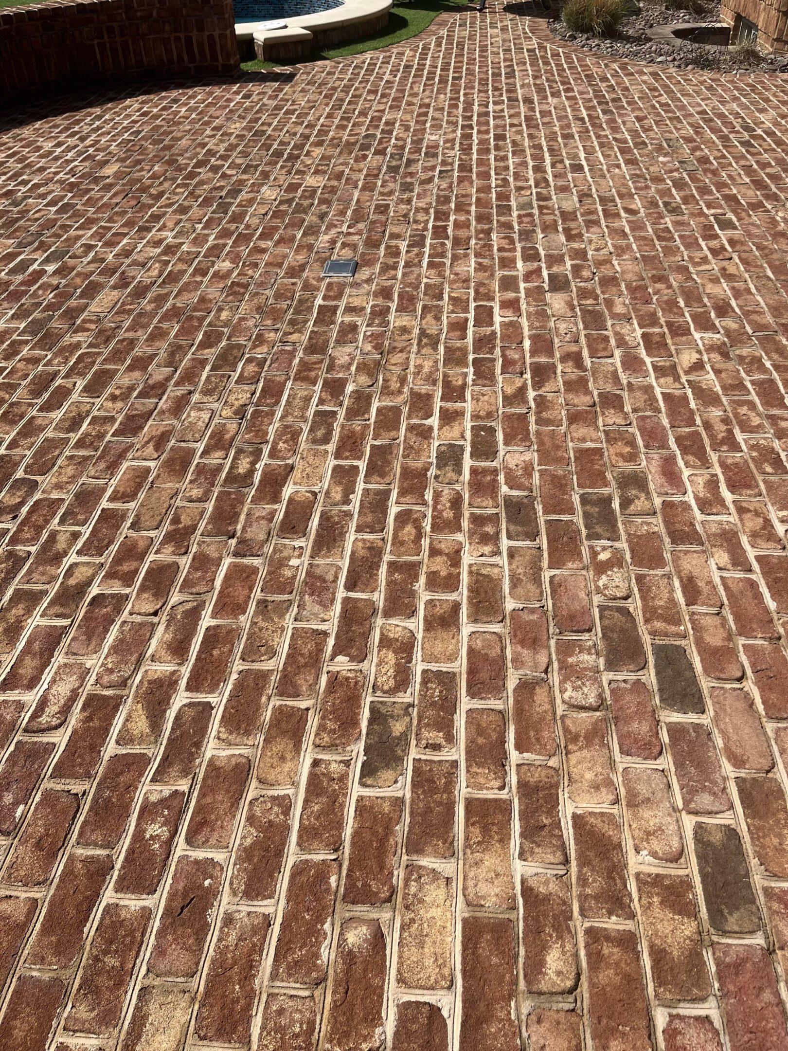 A brick pavement with a mix of red and brown bricks.