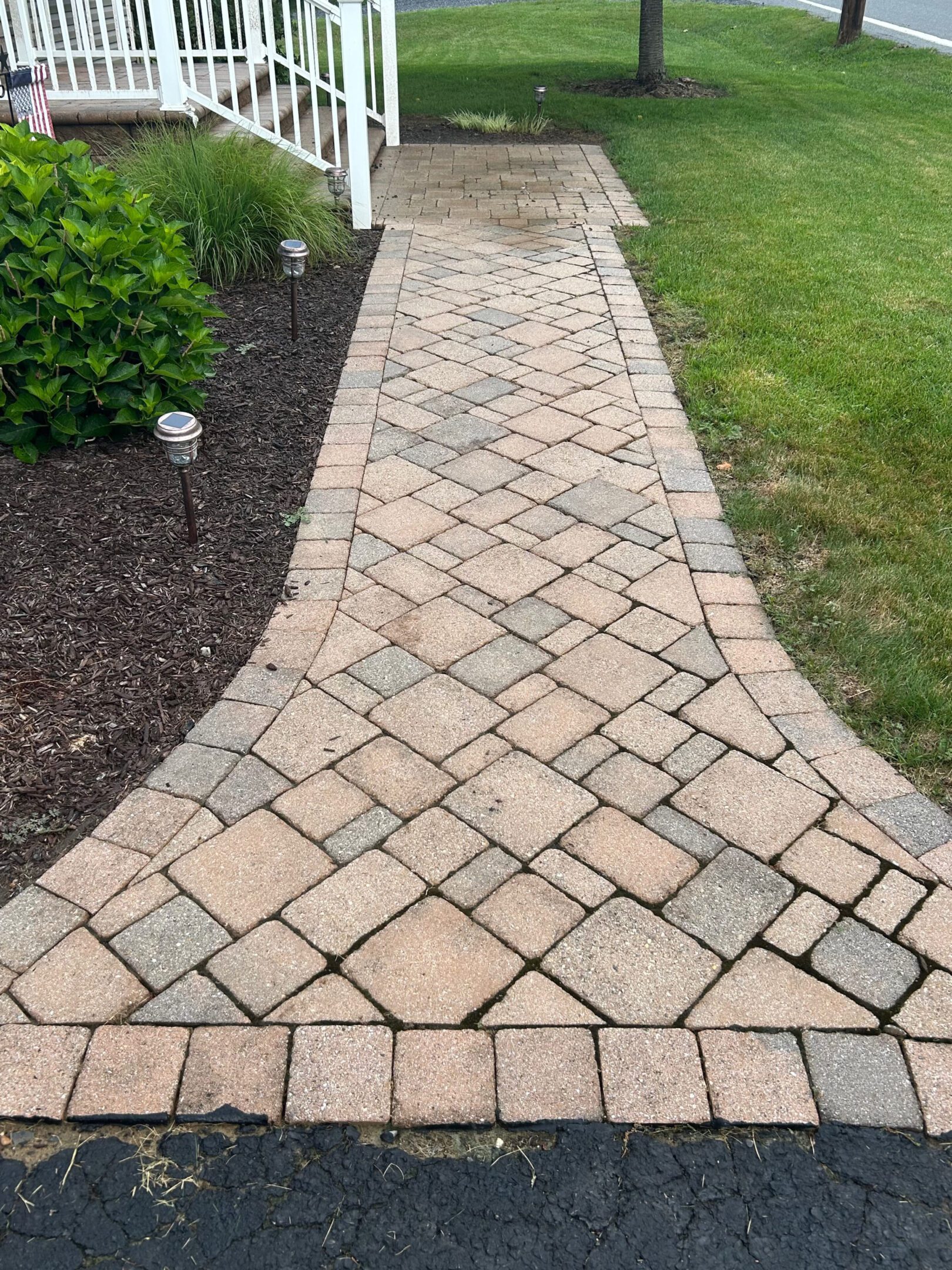 Curved stone pathway with neatly arranged pavers through a garden.