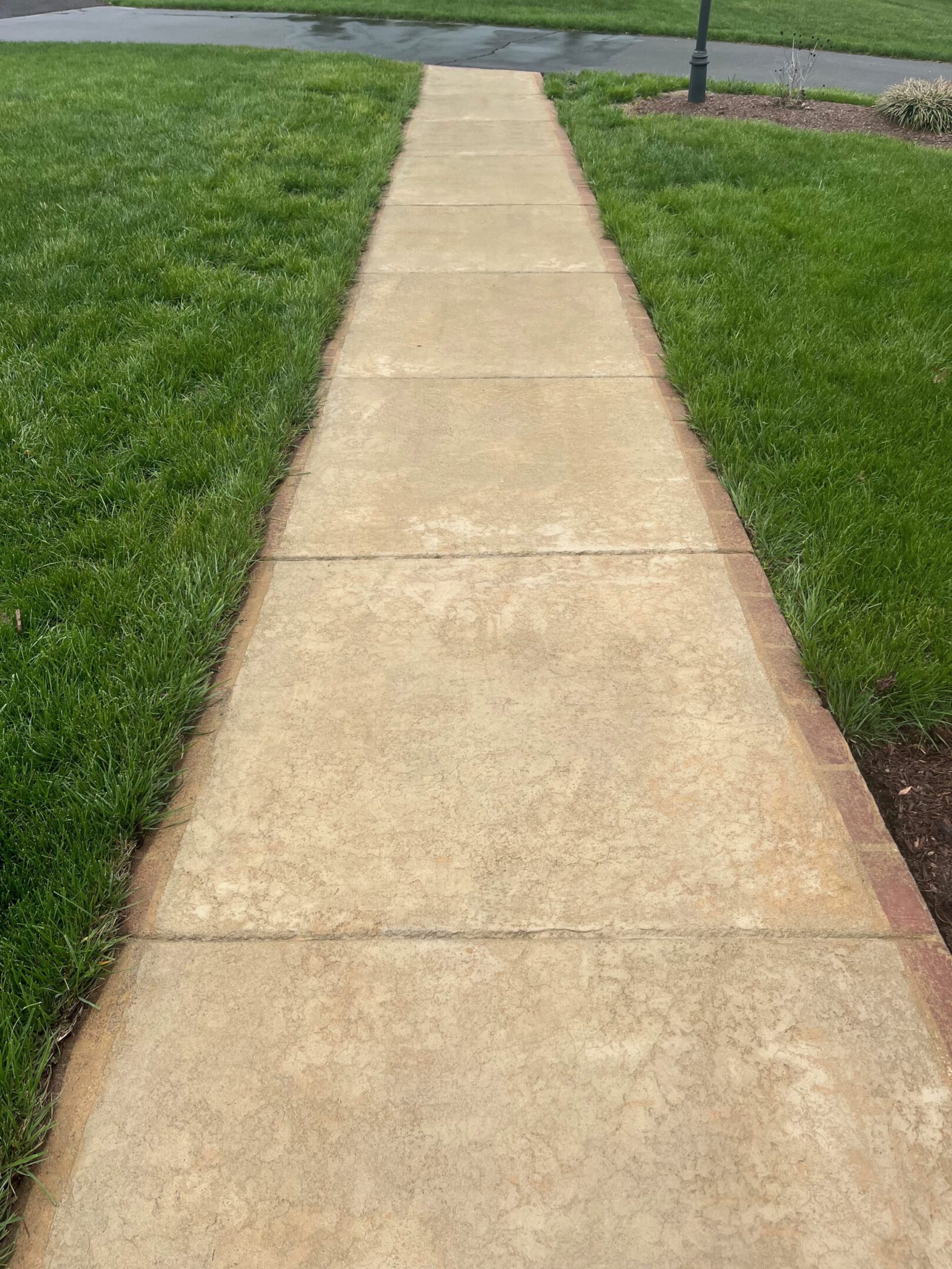 A concrete sidewalk bordered by green grass on both sides.