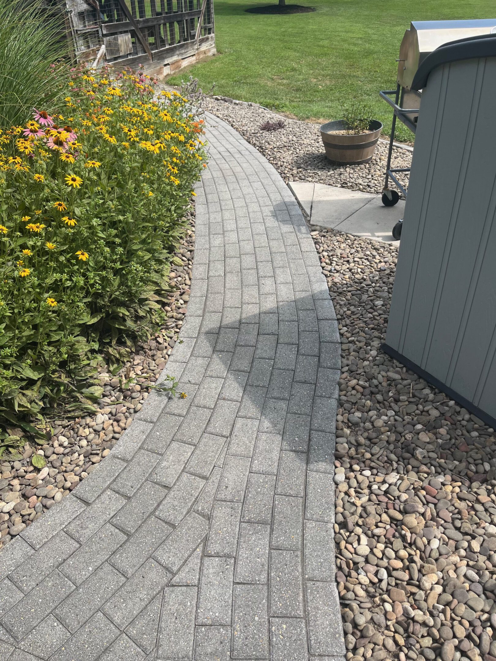 Curved stone pathway beside garden and gravel area.