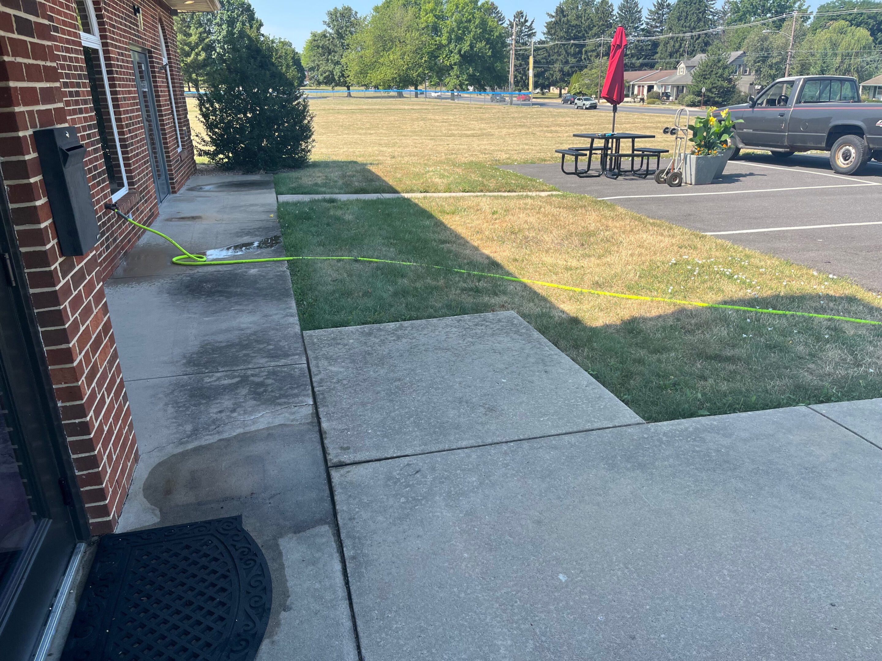 A backyard with a concrete patio and grassy area under a clear sky.