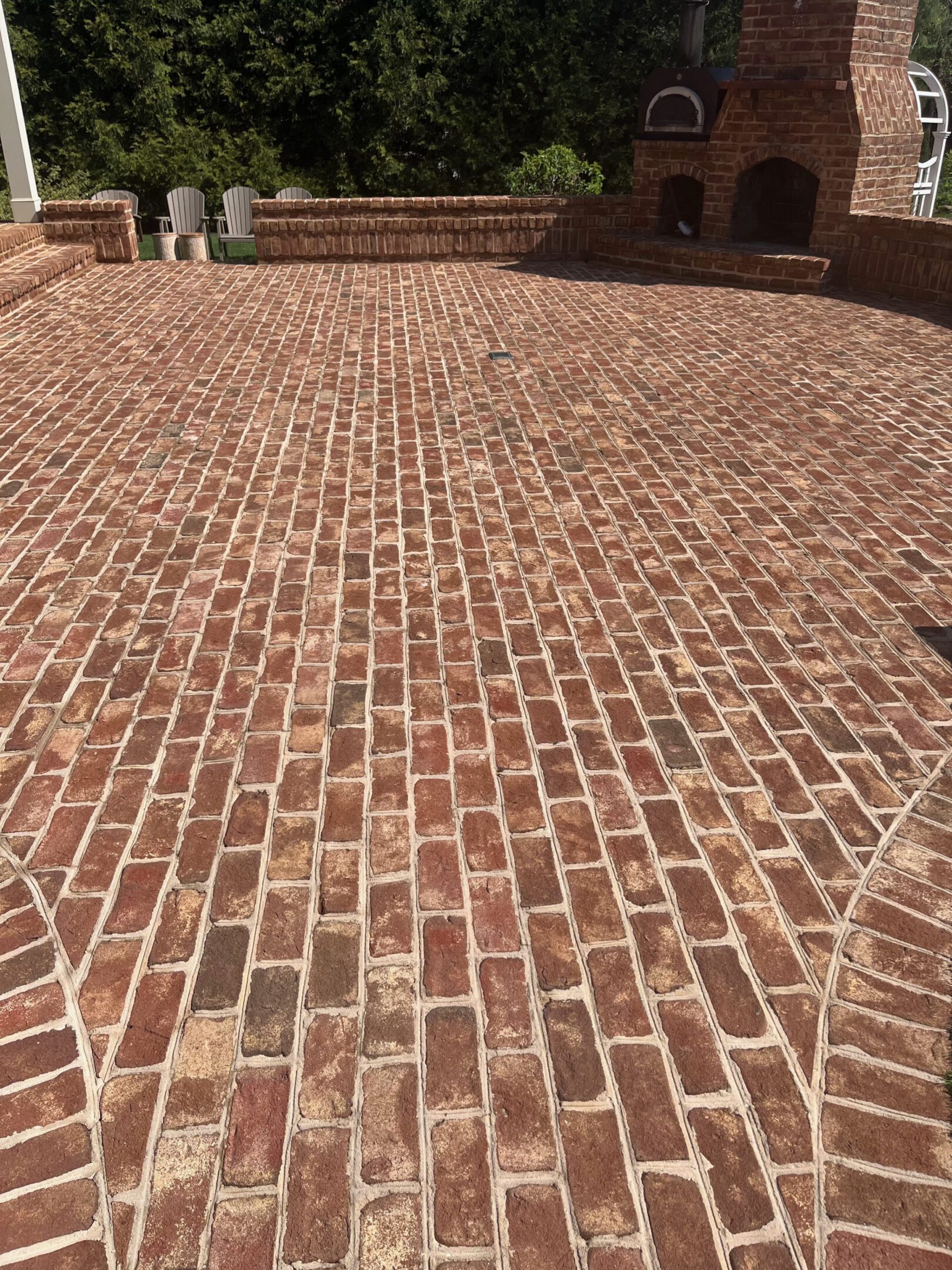 A driveway paved with red bricks in a herringbone pattern.