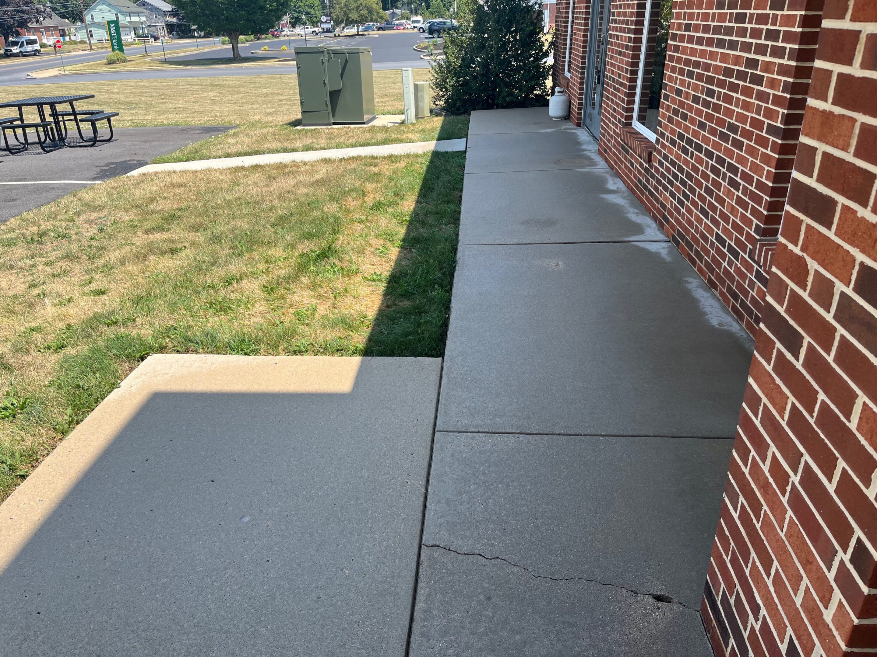 Freshly poured and smoothed concrete sidewalk along a brick building.