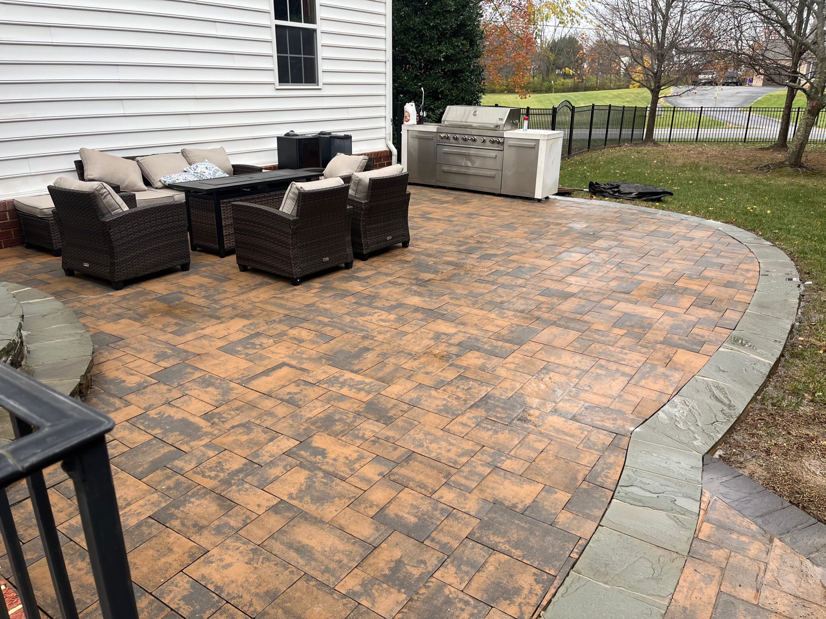 Spacious backyard patio with cozy seating and a hot tub on a patterned stone floor.