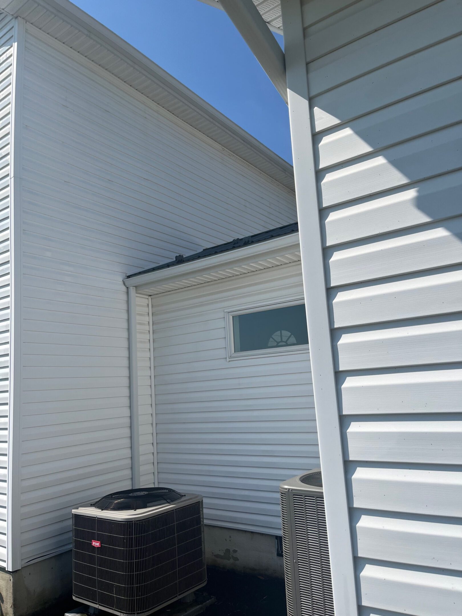 Bright outdoor corner of a white house with air conditioning units.