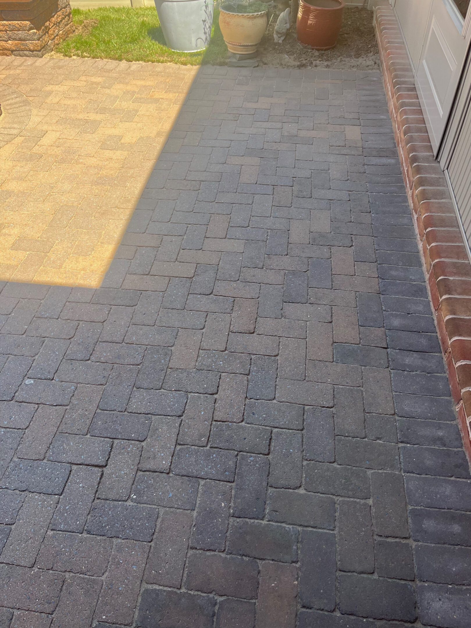 A brick-paved pathway alongside a brick wall with sunlight casting a shadow.