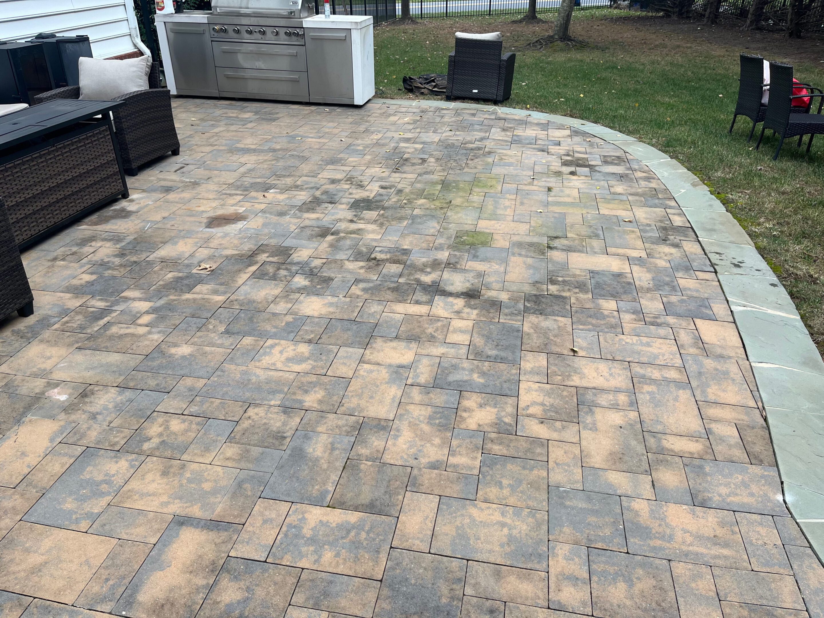 Newly installed patterned stone patio with clean edges and a grassy yard.