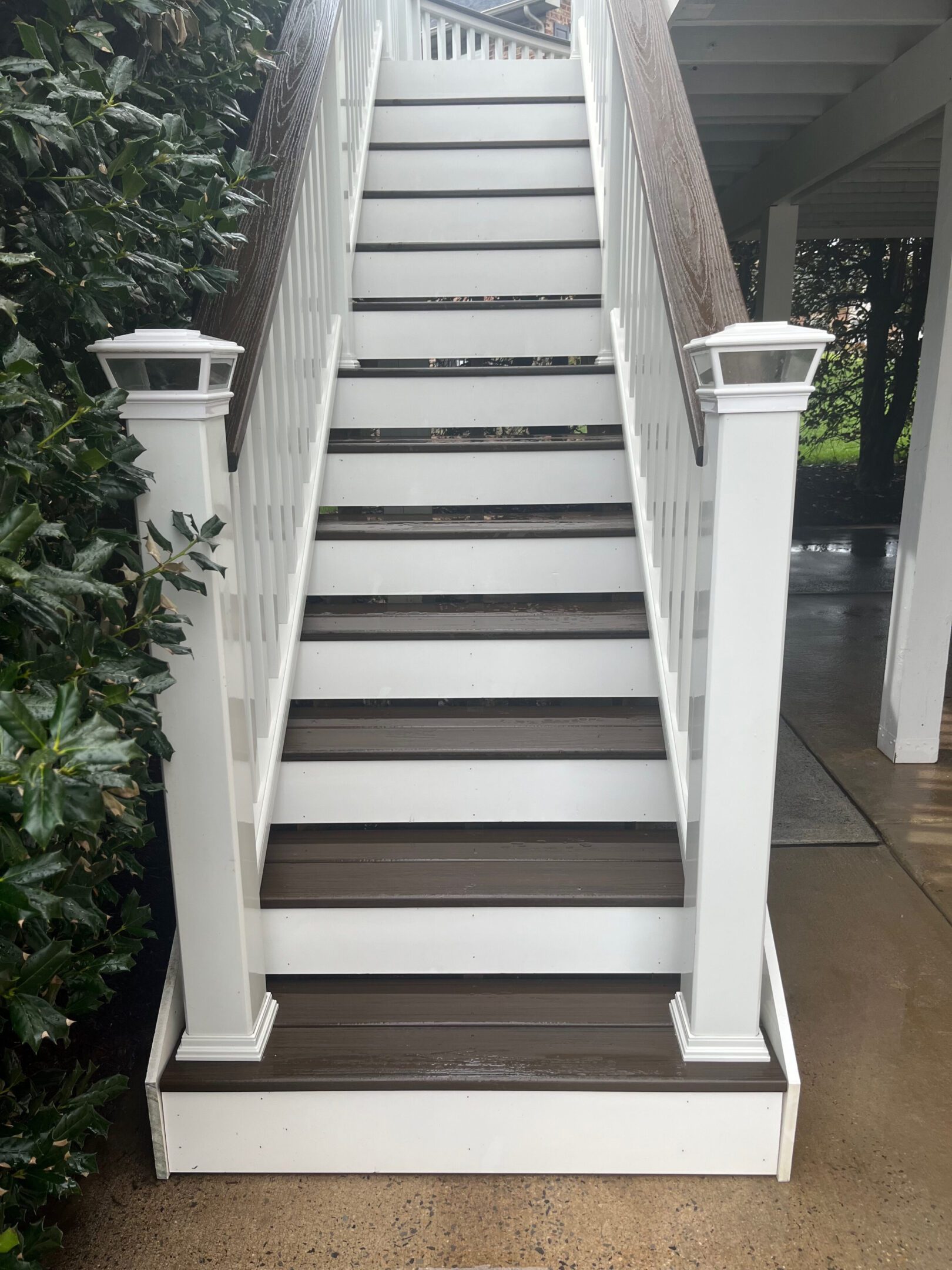 A set of white outdoor stairs with dark wooden steps and railings.