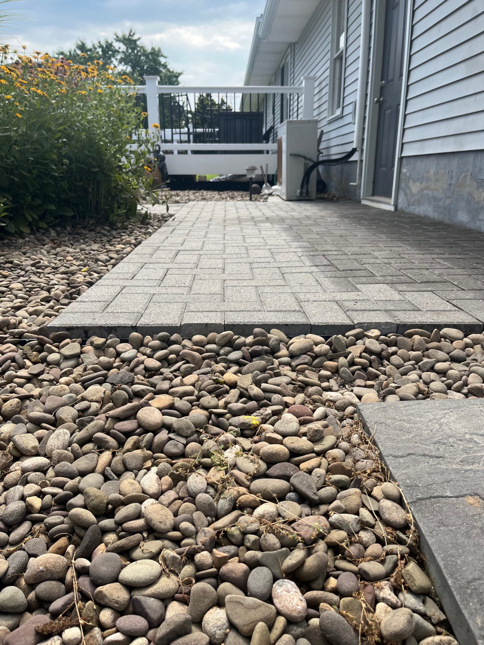 Stone pathway with pebbled border beside a house.