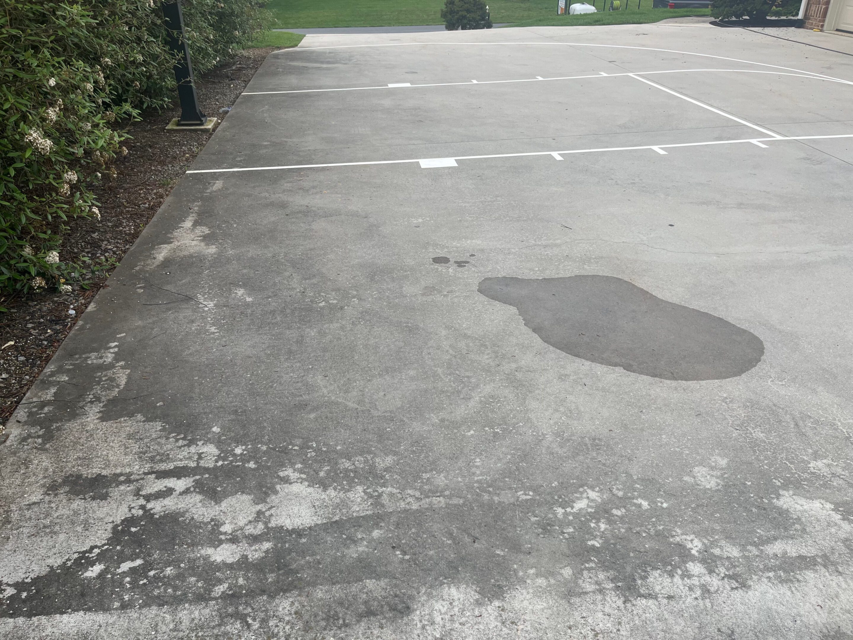 Empty outdoor basketball court with visible cracks and stains on the surface.