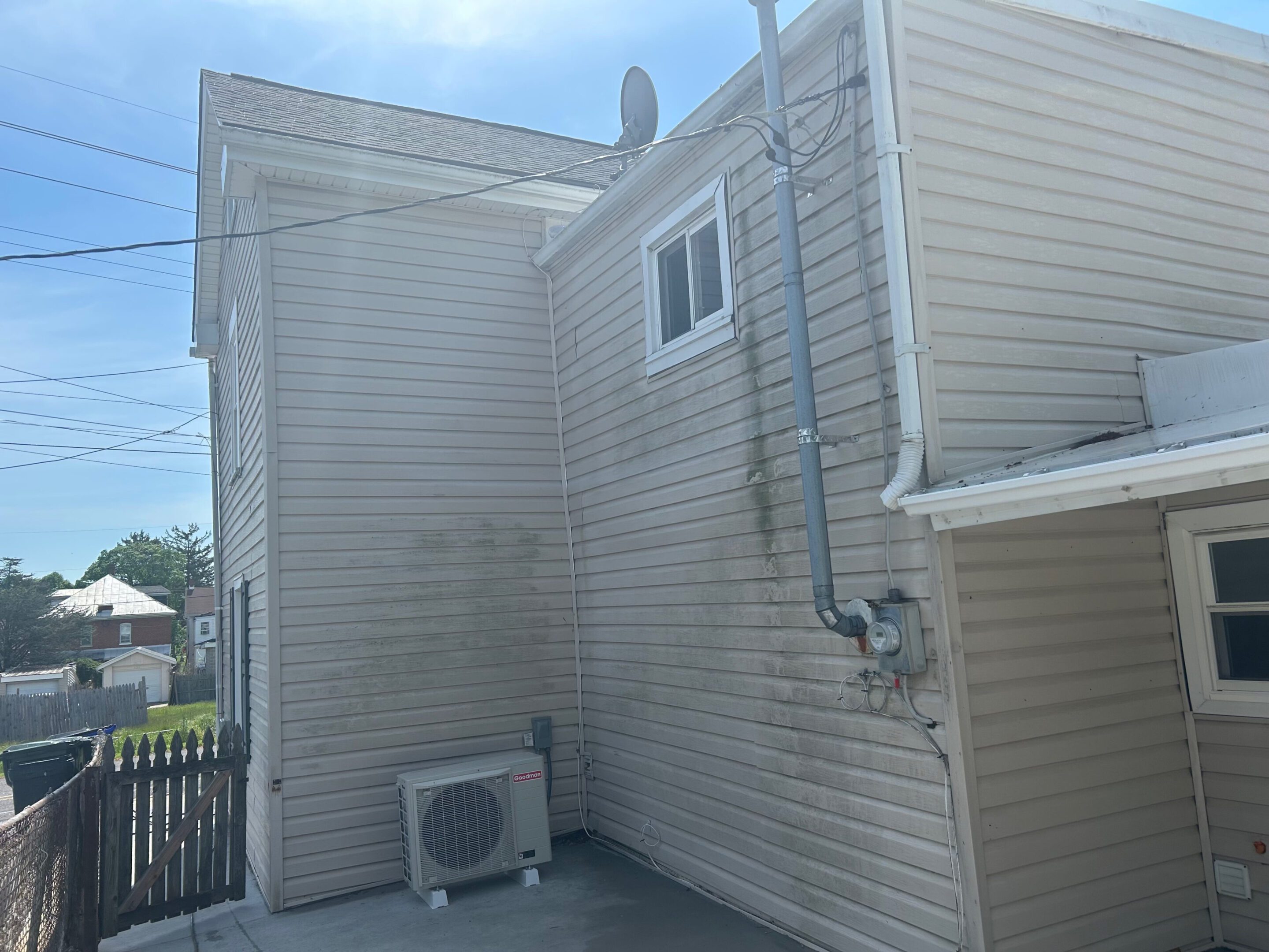 Side of a house with beige siding and an air conditioning unit.