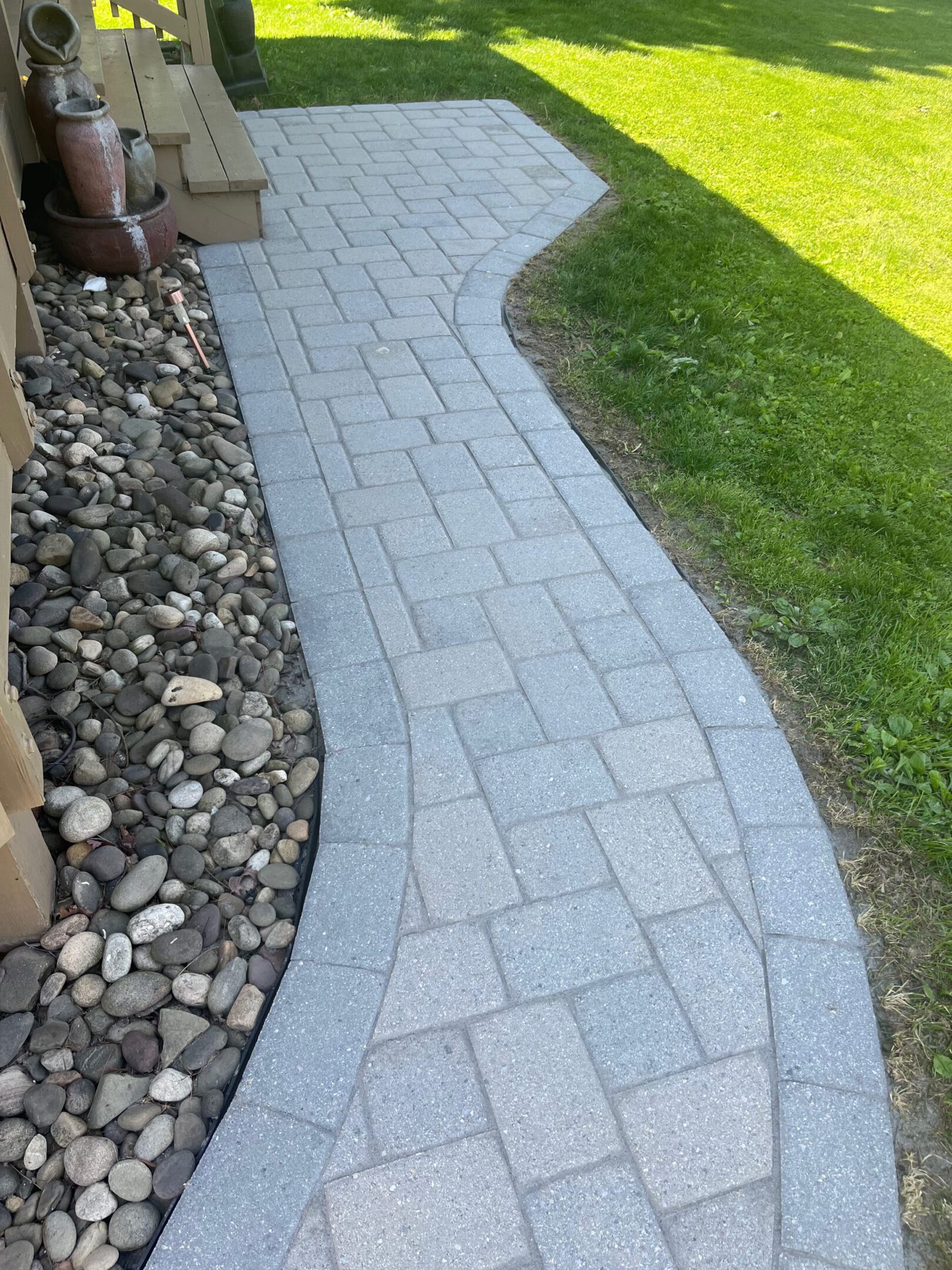 Curved stone pathway bordered by green grass and decorative rocks.