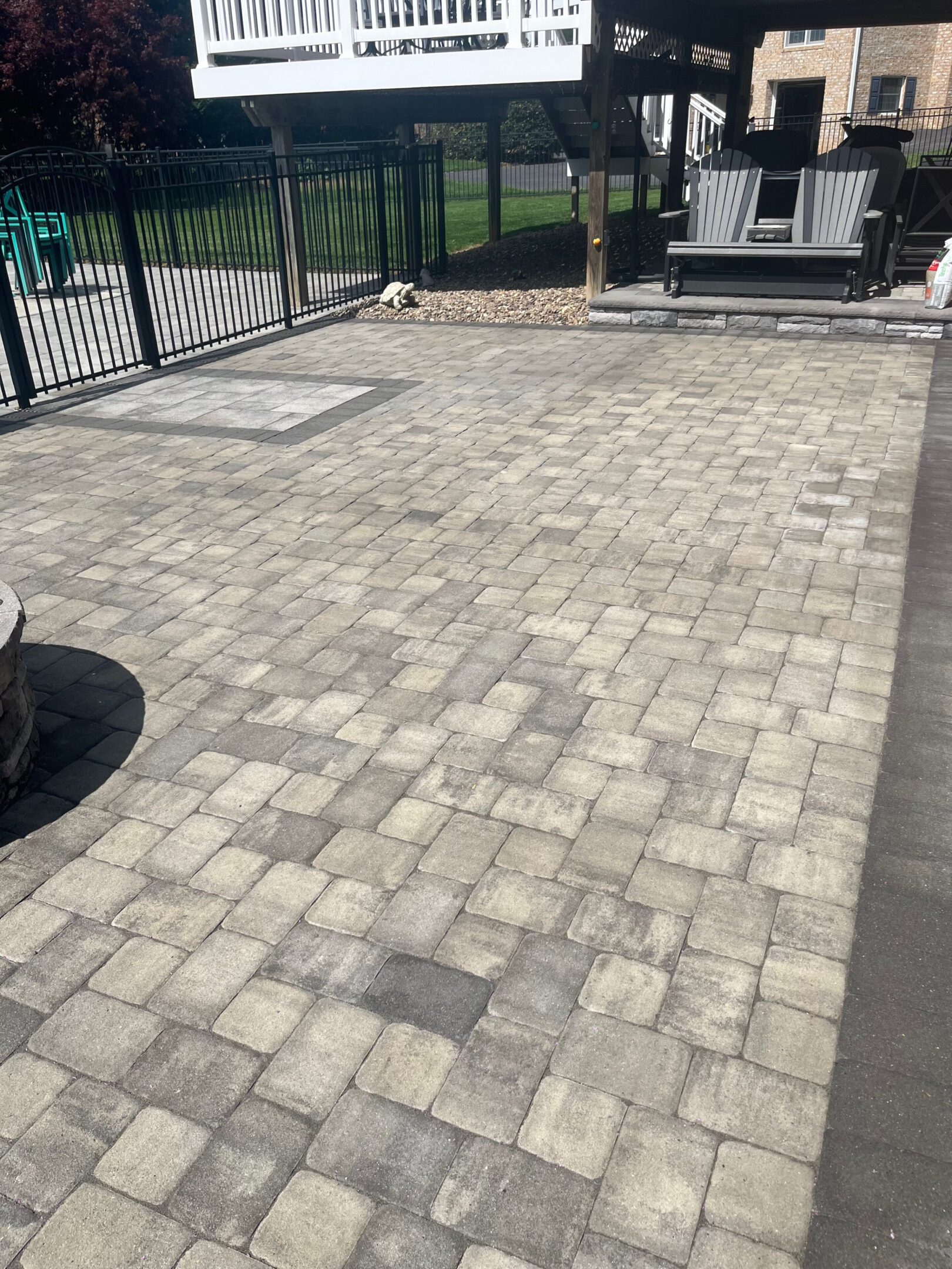 A paved patio area with stone tiles and a black metal fence.