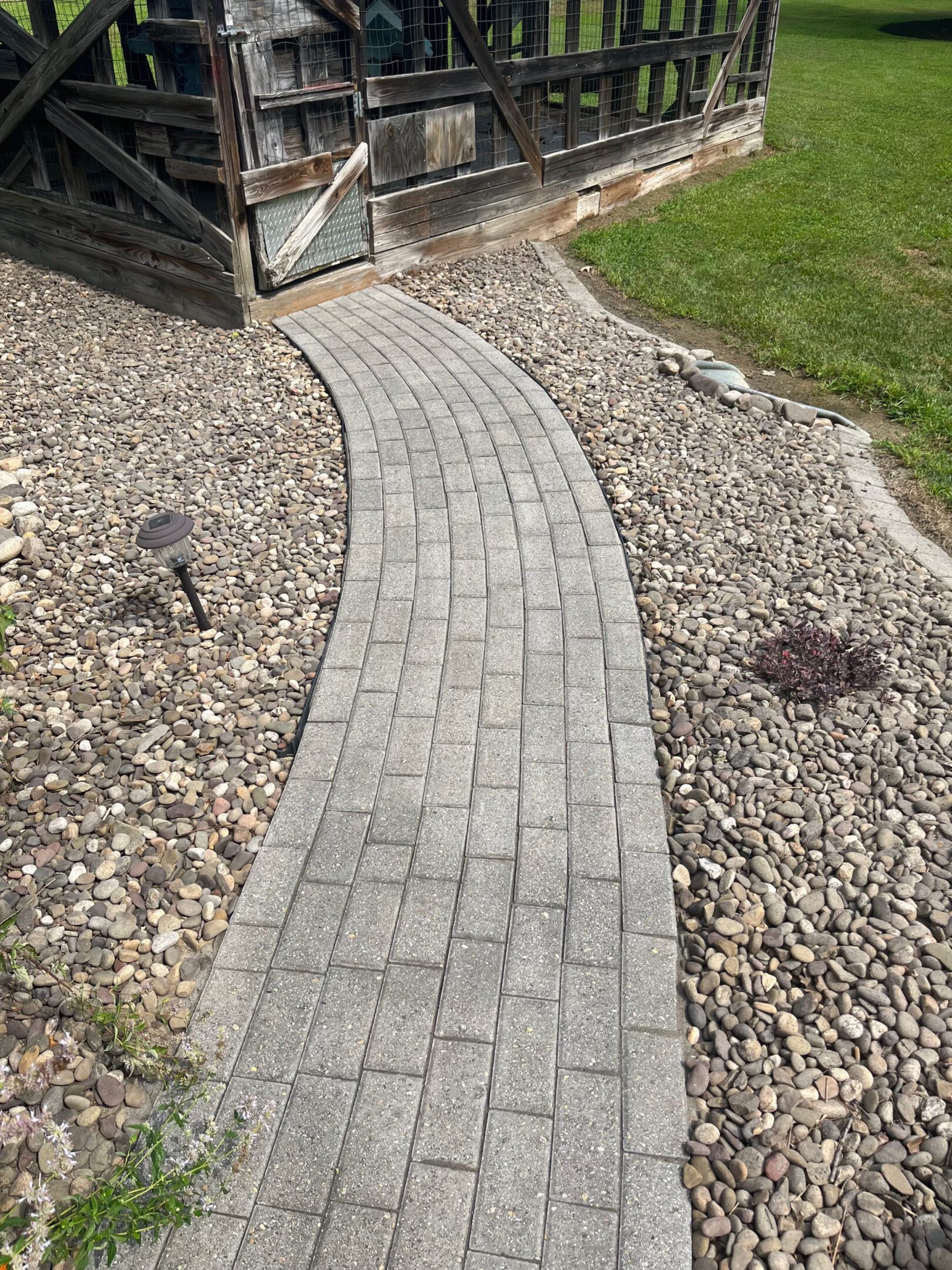 Curved stone pathway bordered by rocks and grass.