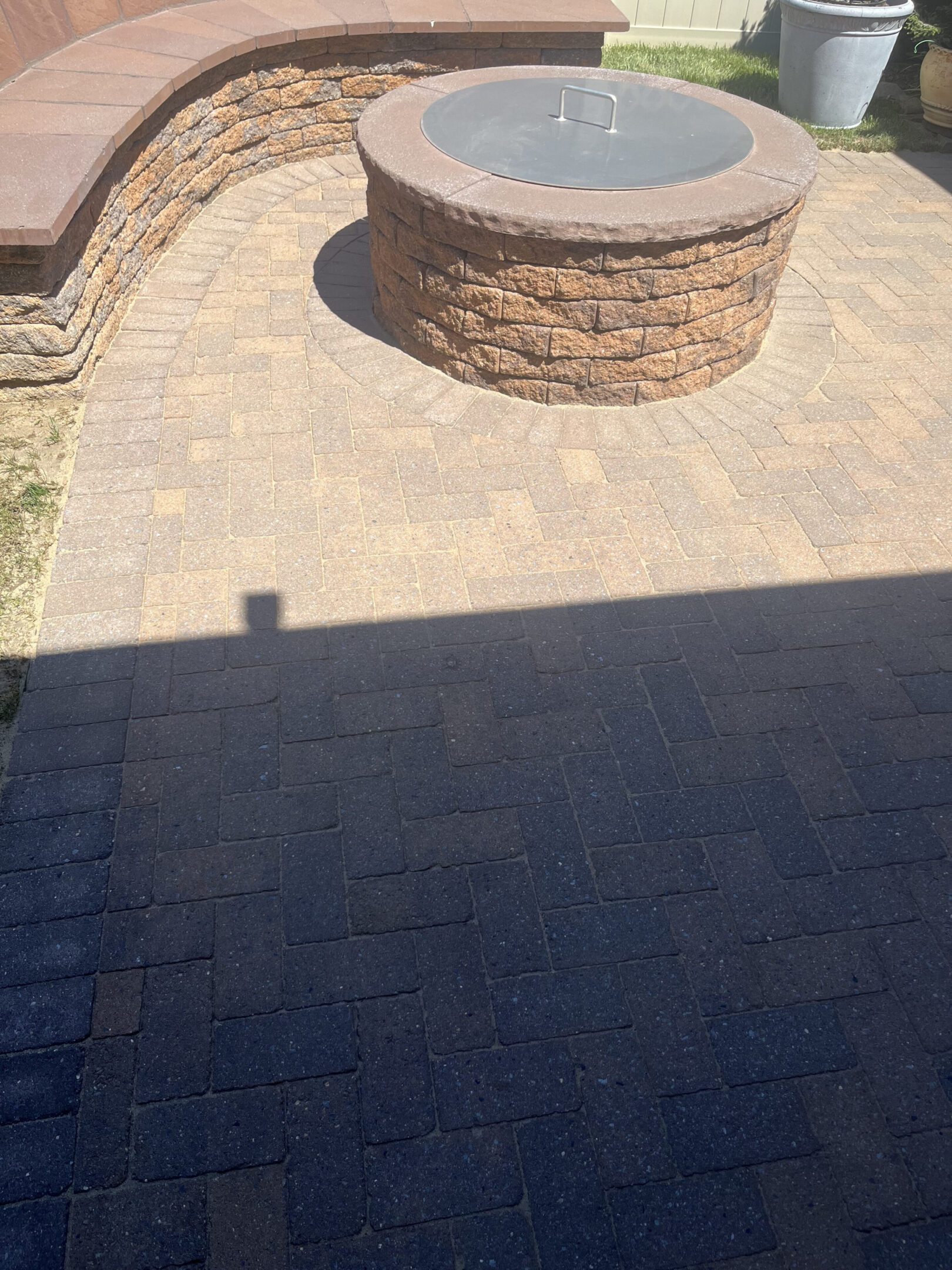 Stone patio with a circular stone fire pit in sunlight.